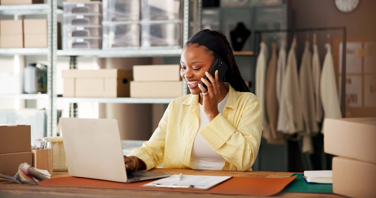 Business owner managing orders and client conversations from a laptop and phone
