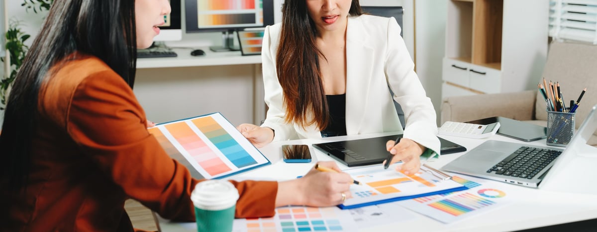 Two designers reviewing a colour palette and interface layouts together in a bright studio