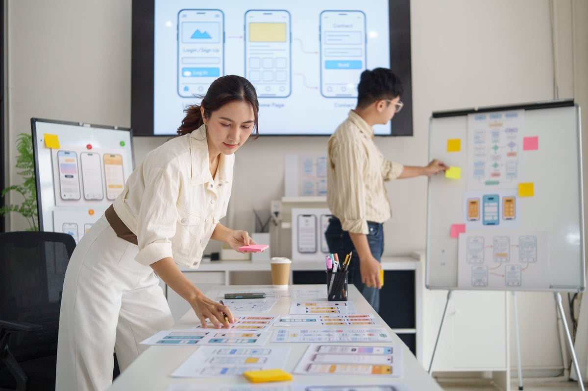Designer writing notes while planning an interface on paper